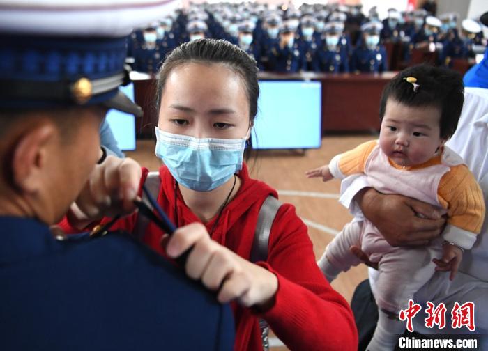 新消防員楊振的妻子彭莉與女兒現(xiàn)場(chǎng)見(jiàn)證丈夫加入“火焰藍(lán)”的神圣時(shí)刻。　劉忠俊 攝