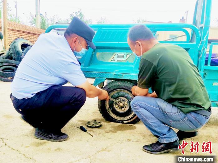 賽旦與民警共同維修三輪摩托車。　依力哈木江 攝